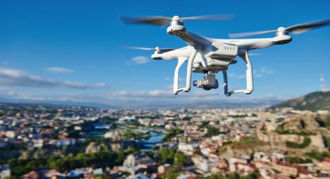 drone with digital camera flying or hovering in blue sky over the city