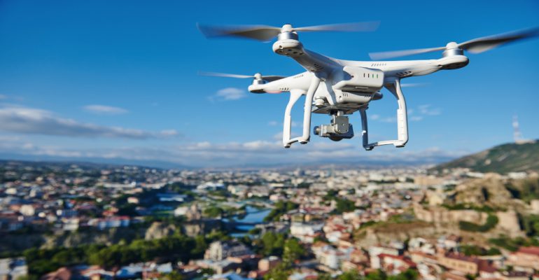 drone with digital camera flying or hovering in blue sky over the city
