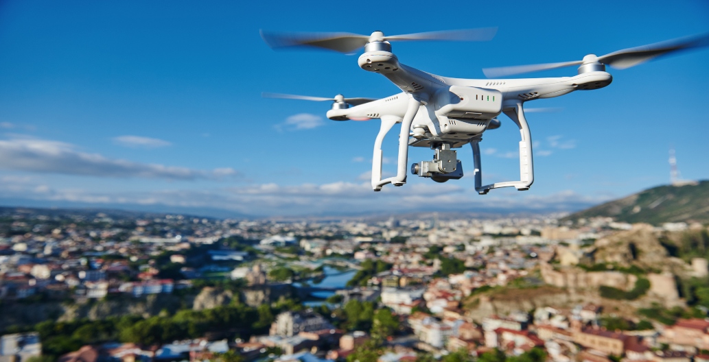 drone with digital camera flying or hovering in blue sky over the city