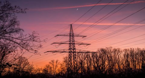Silhouette of poles and power lines in the sunset